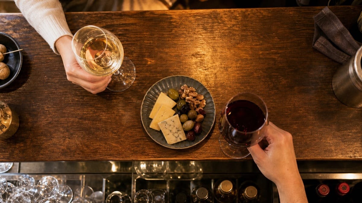 立ち飲みカウンターに並ぶ赤白のグラスワインと小皿のおつまみ